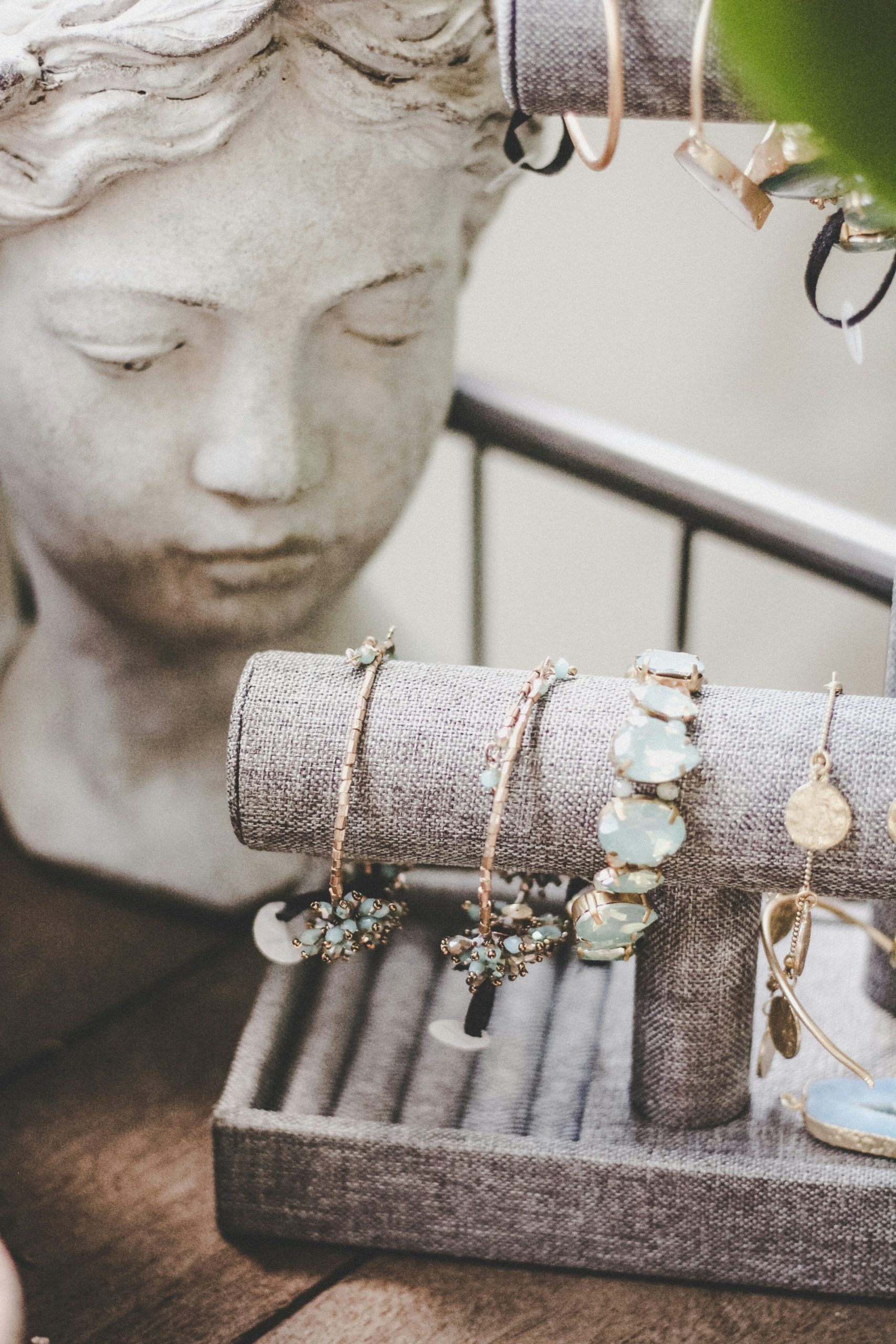 Artisan necklaces, ceramic earrings, a sandalwood hairpin and jewelry box displayed on gray linen stands